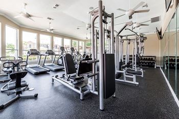 A gym with a variety of equipment including treadmills, weights, and exercise machines.